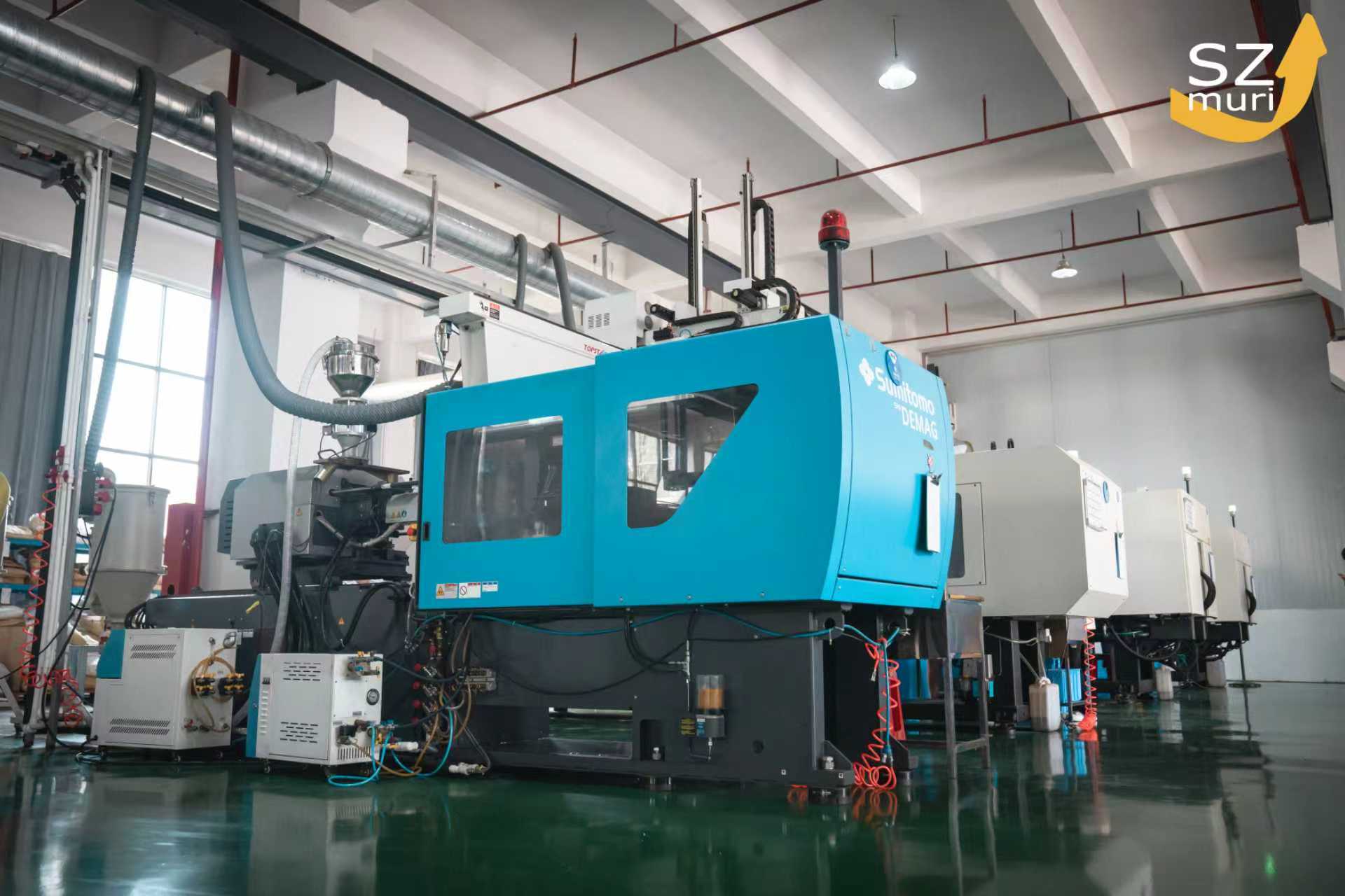 Eine große blaue Spritzgussmaschine steht in einer modernen hellen Fabrikhalle